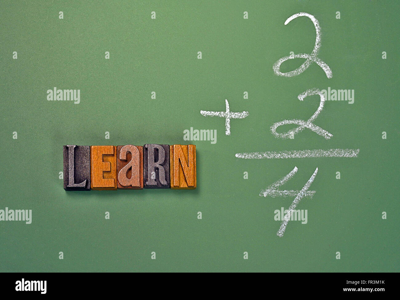The word learn in vintage wooden letterpress type with simple math problem on green chalkboard. Stock Photo