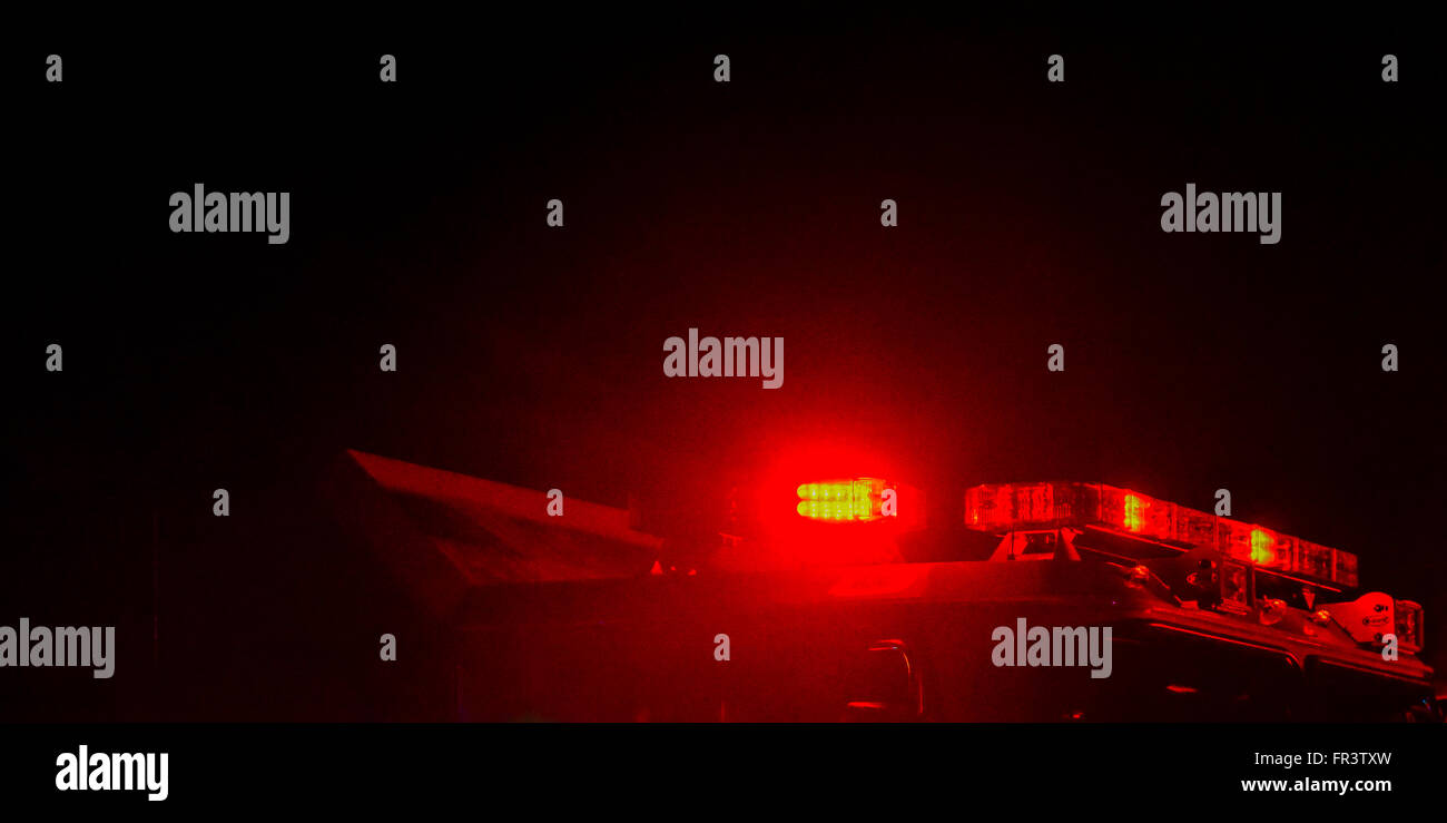 Red flashing police car lights atop a patrol car at night while