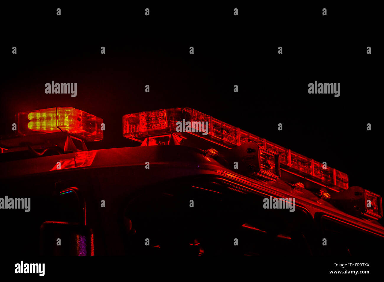 Red flashing police car lights atop a patrol car at night while