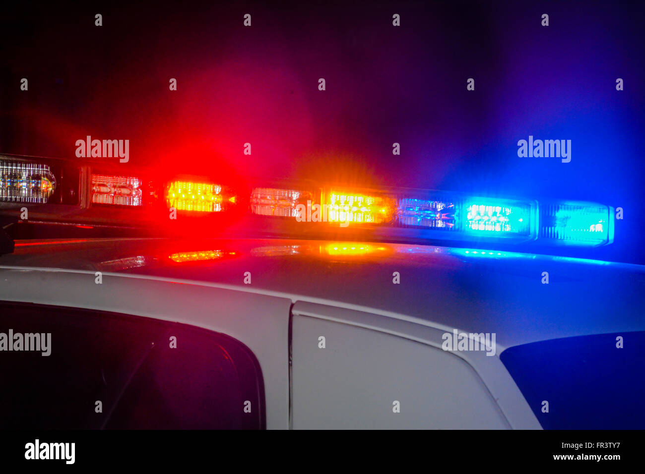 Red and blue flashing police car lights atop a patrol car at night