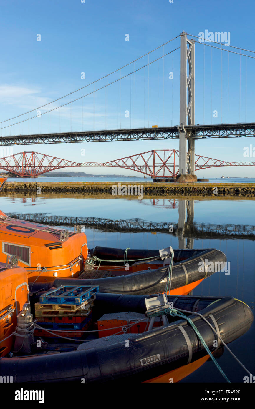 The Forth Road Bridge and the Forth Rail Bridge over the Firth of Forth, near Edinburgh, with the bows of two boats. Stock Photo