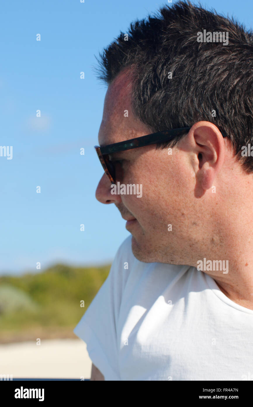 A man looking away from the camera and beach in the background Stock Photo