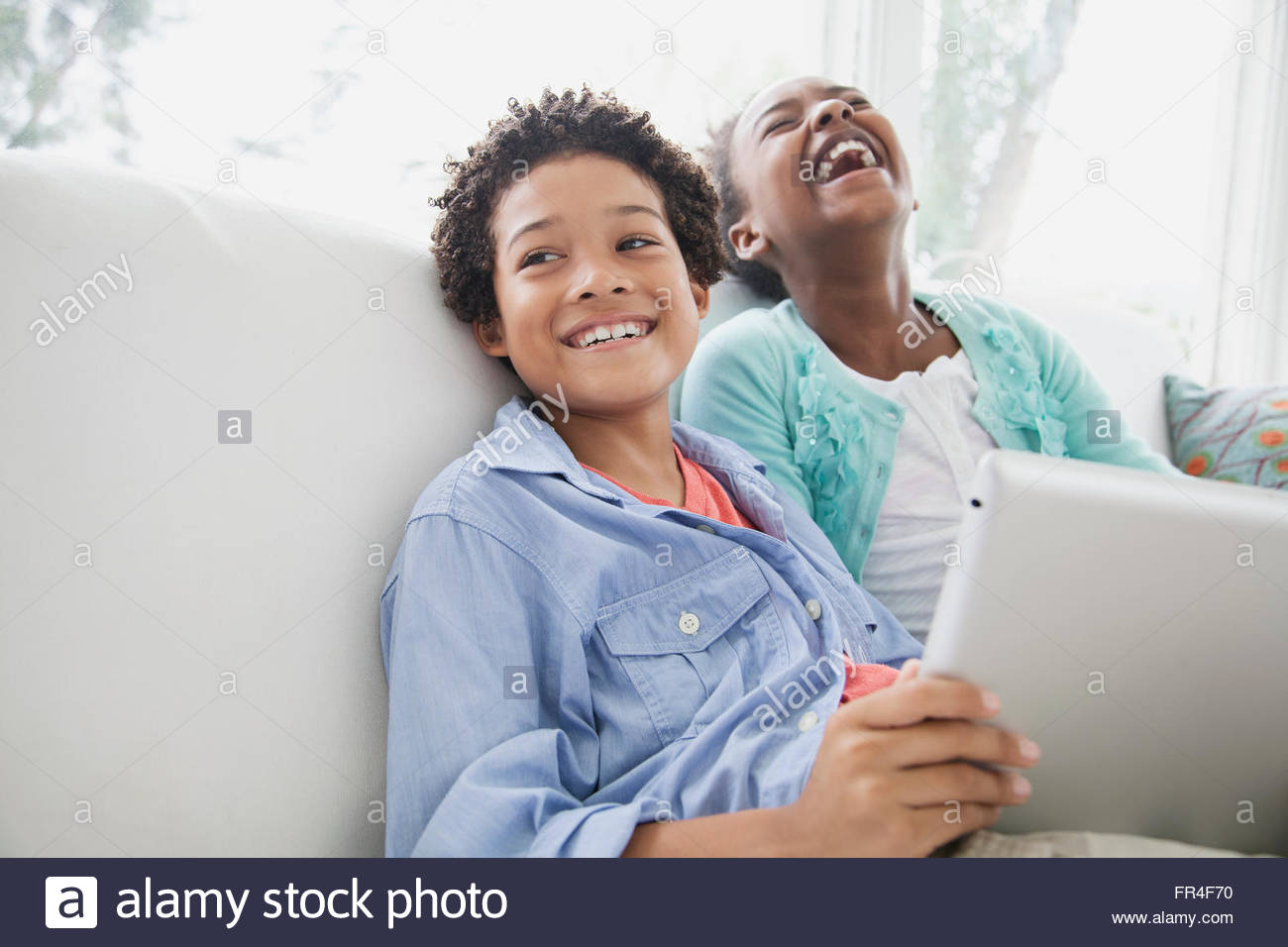 sister and brother having a laugh browsing pc tablet Stock Photo