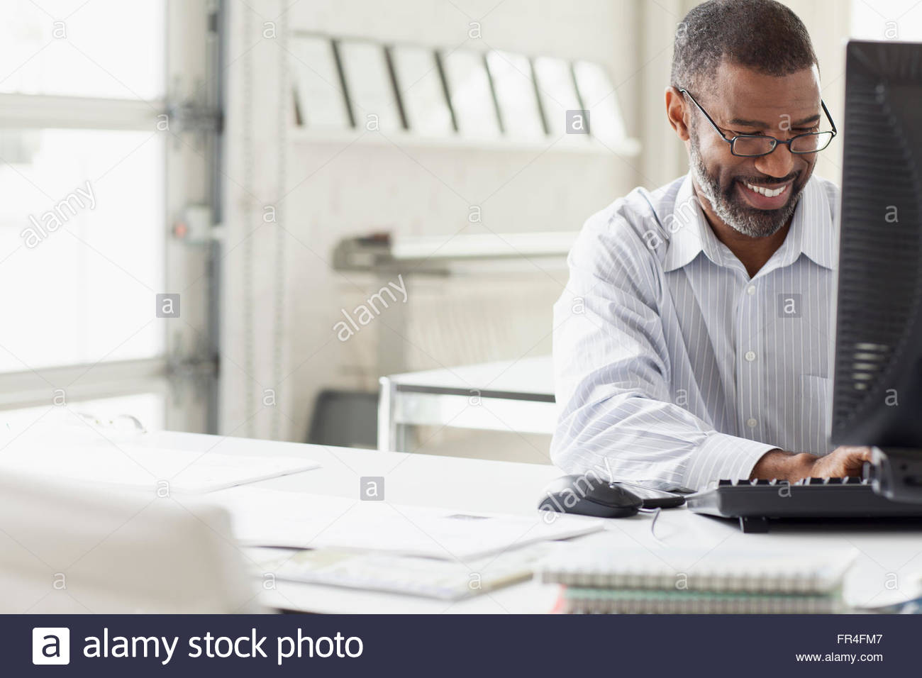 attractive businessman smiling as he keyboards Stock Photo