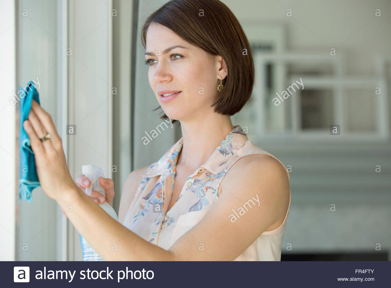 Woman using spray cleaner on white walls. Stock Photo