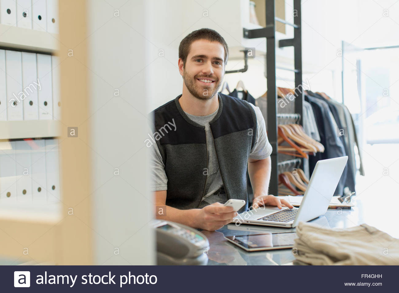 Bearded clerk with laptop, pc tablet and cell phone at desk. Stock Photo