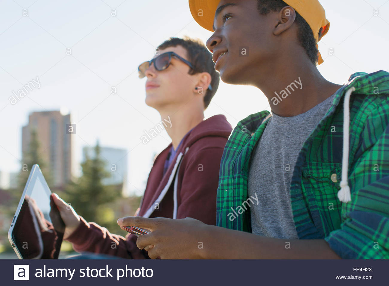 teenage boys using wireless technology at city park Stock Photo - Alamy