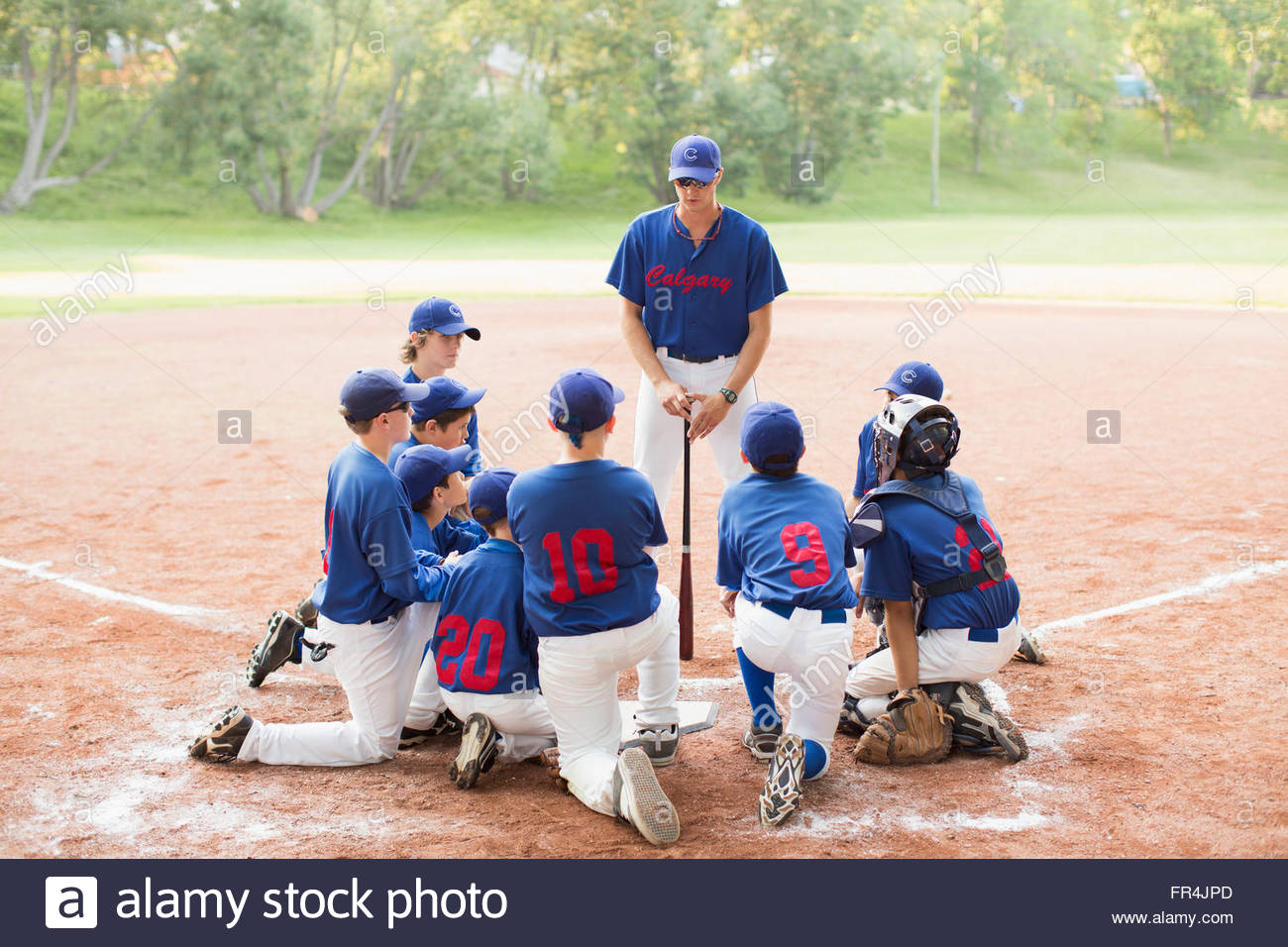 Youth baseball coach talks to team Stock Photo - Alamy