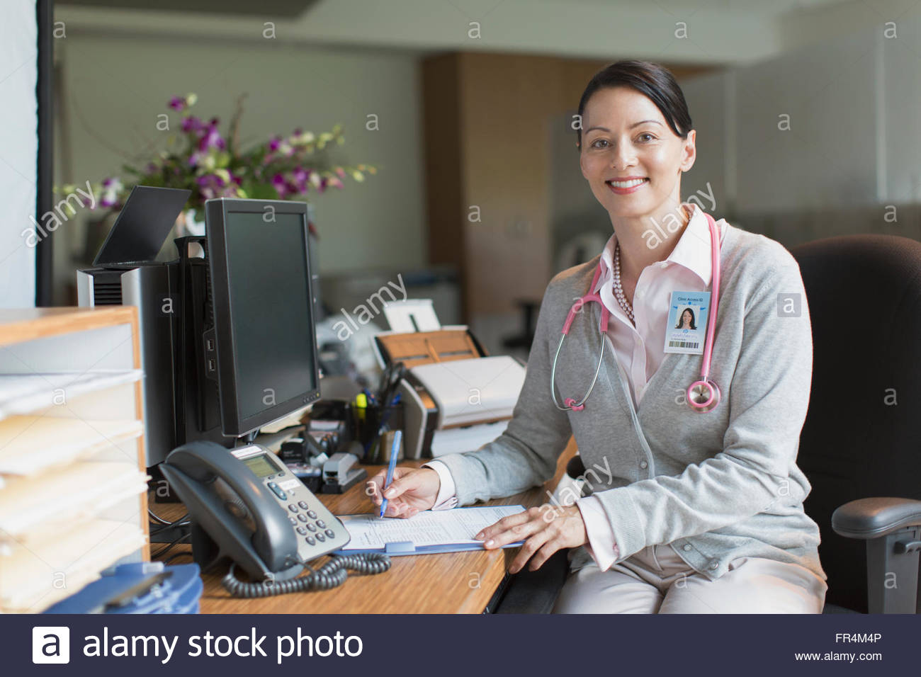 female doctor filling in chart at desk Stock Photo