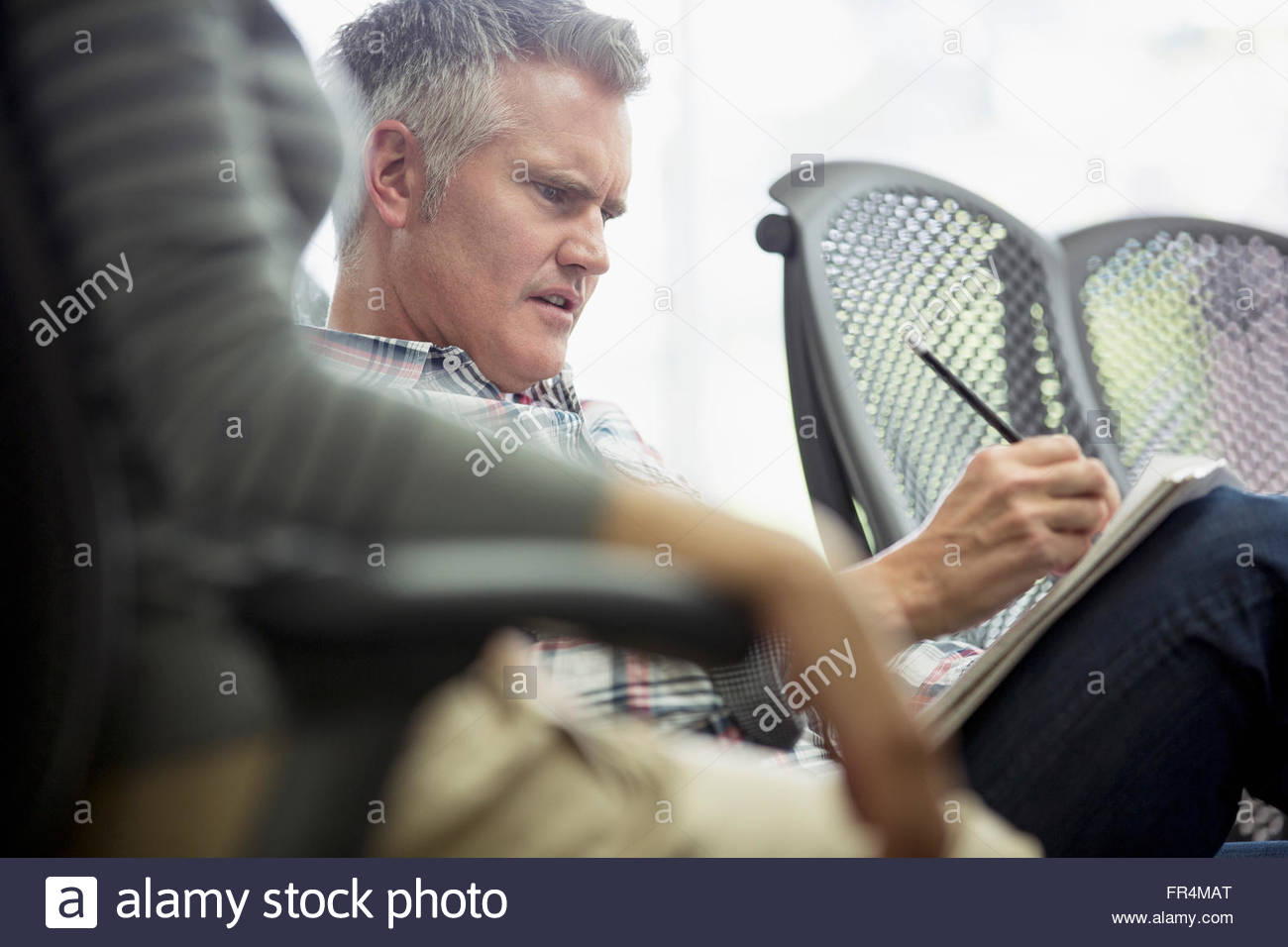 coworkers with confused look taking notes at meeting Stock Photo