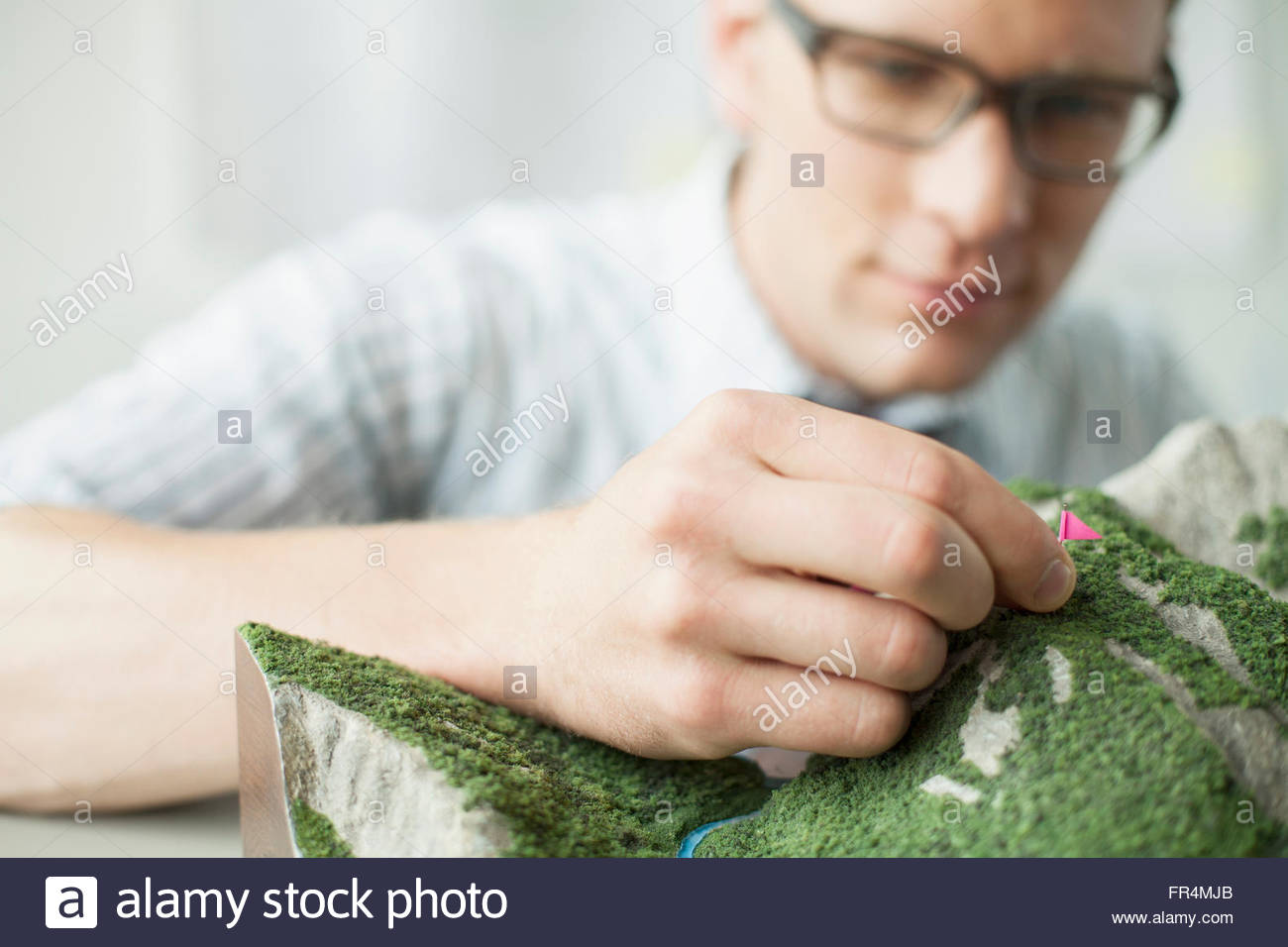 young architect putting flags on topographical model Stock Photo