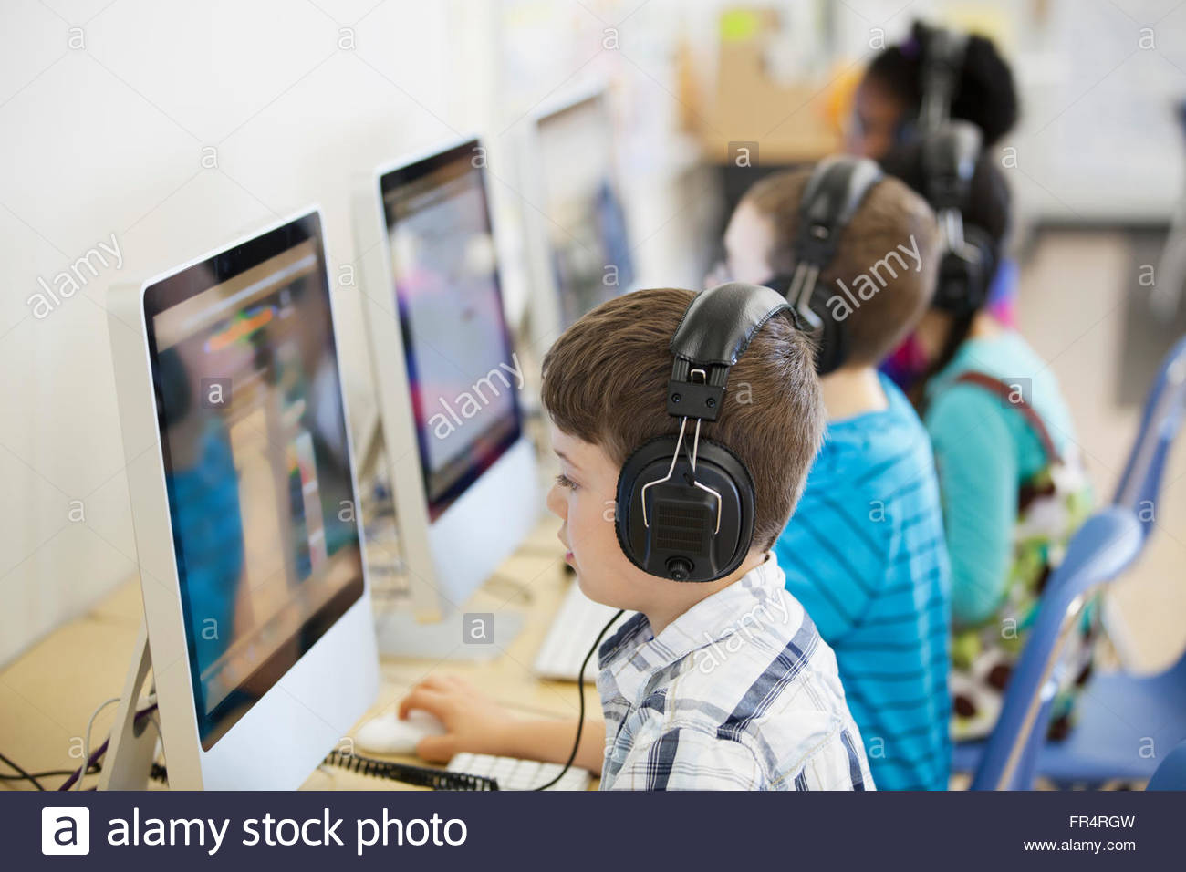 elementary students with headphones in computer lab Stock Photo Alamy