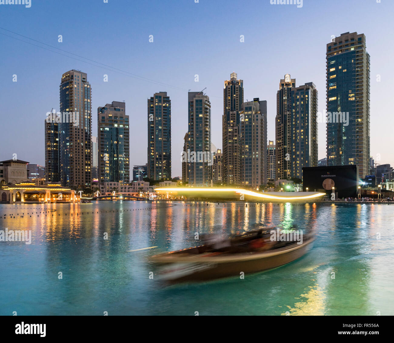 Night view of  luxury apartment towers and tourist boat trip on lake in Downtown Dubai United Arab Emirates Stock Photo