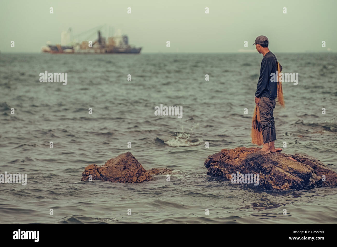 Lonely fisherman gazes out to sea. Stock Photo