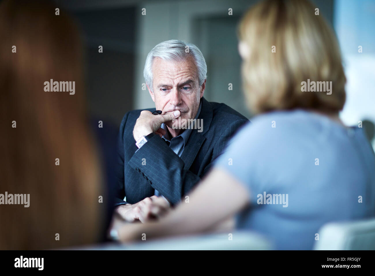 Serious senior businessman looking down in meeting Stock Photo