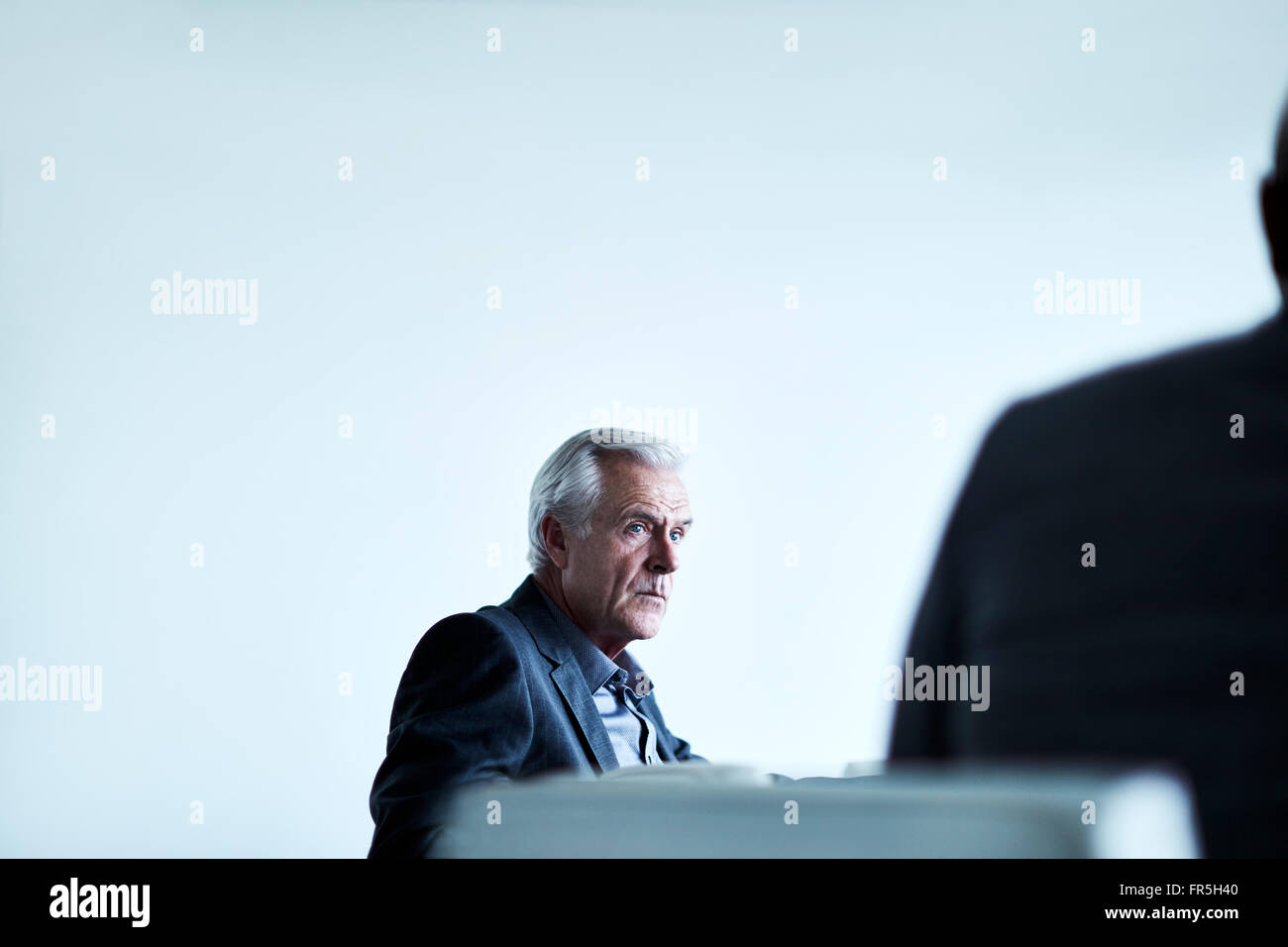 Serious senior businessman listening in meeting Stock Photo