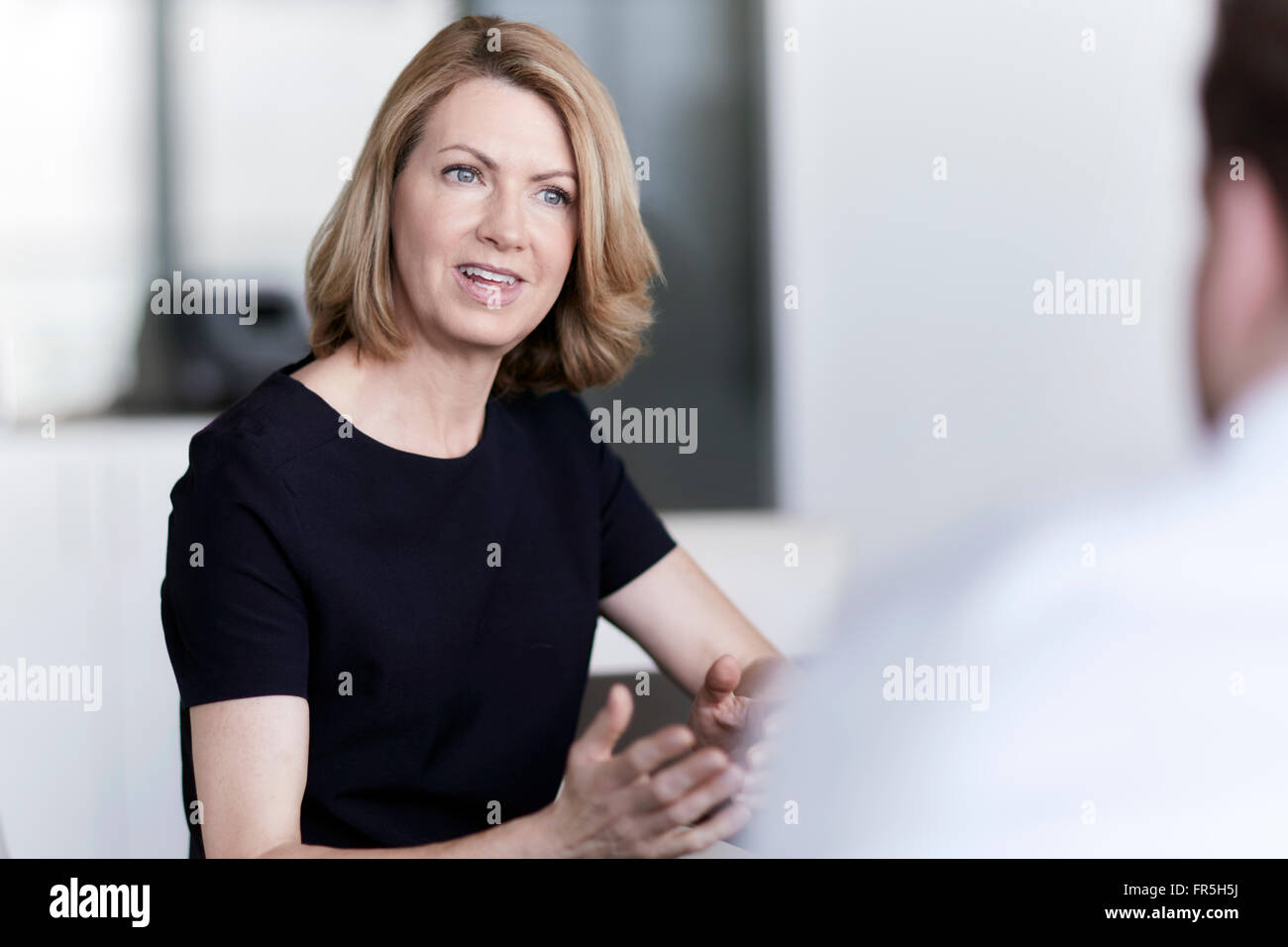 Businesswoman gesturing and talking to businessman Stock Photo