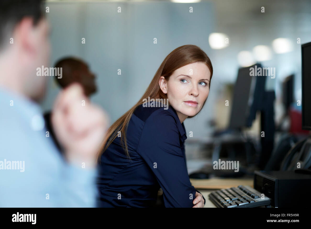 Businesswoman at computer listening to businessman Stock Photo