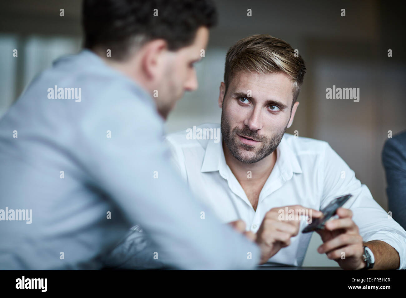 Businessmen discussing part in meeting Stock Photo