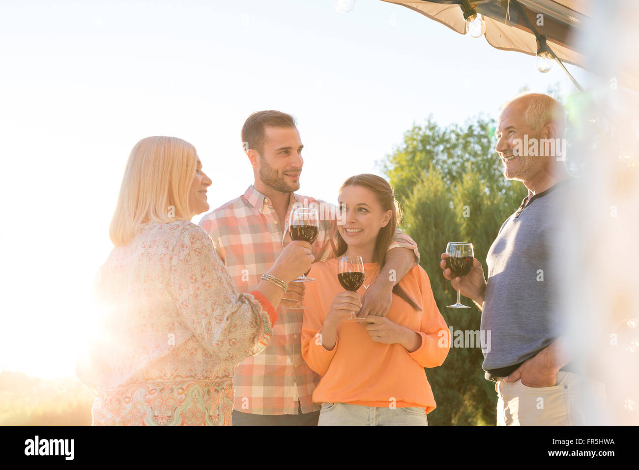 Family talking and drinking wine on sunny patio Stock Photo