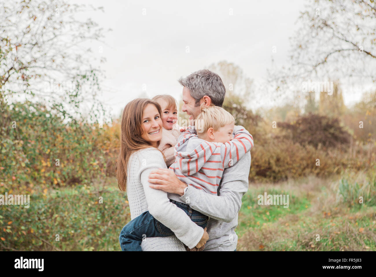 Smiling family hugging in autumn park Stock Photo