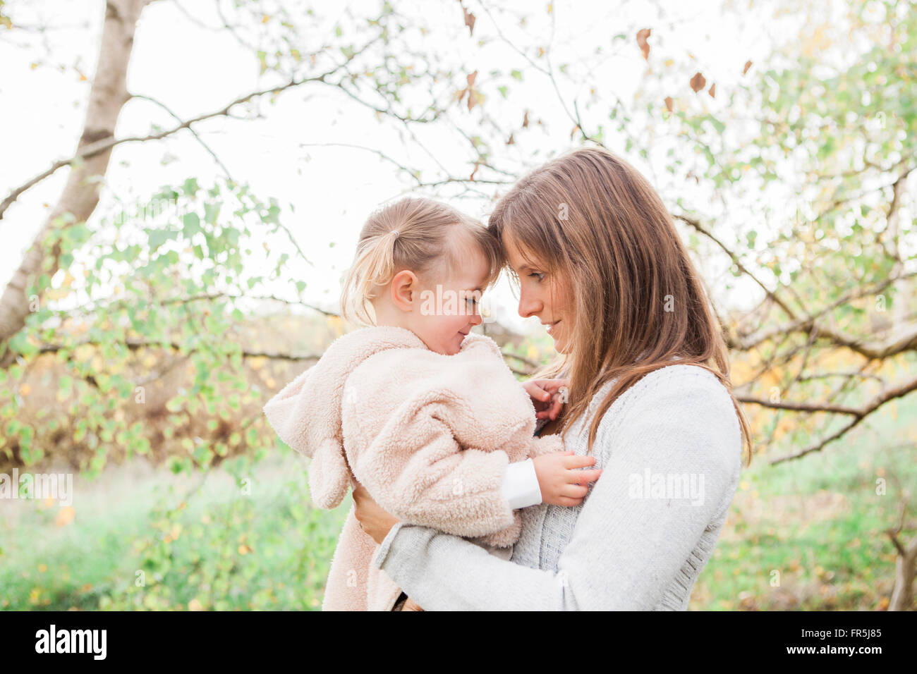 Affectionate mother holding toddler daughter in park Stock Photo