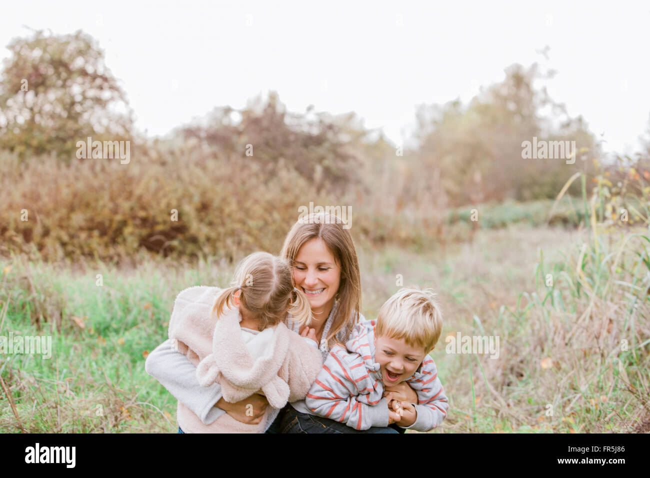 Mother and toddler children hugging in autumn park Stock Photo