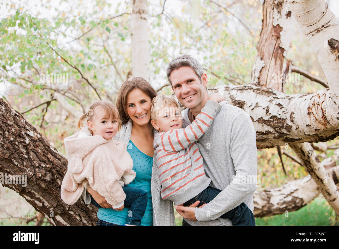 Portrait smiling family in front of tree Stock Photo