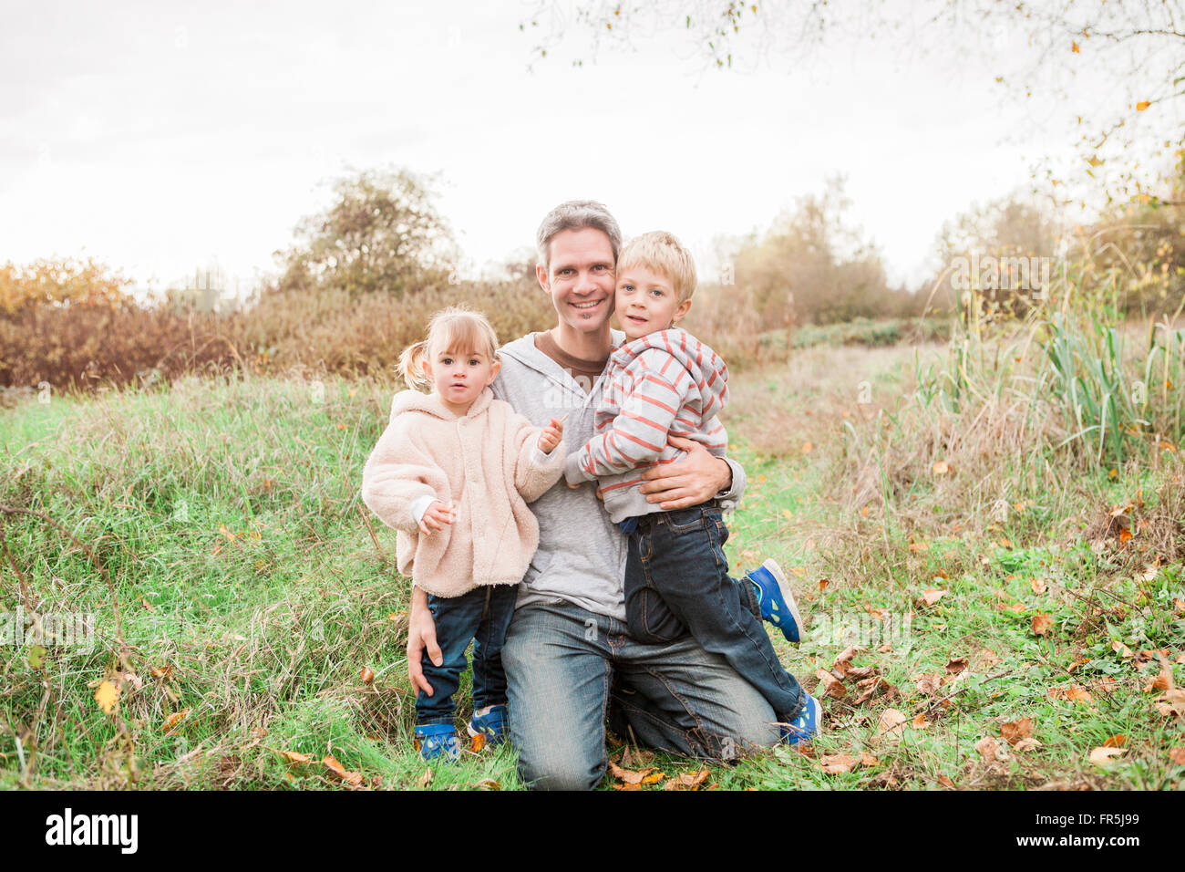 Portrait smiling father and toddler children in autumn park Stock Photo