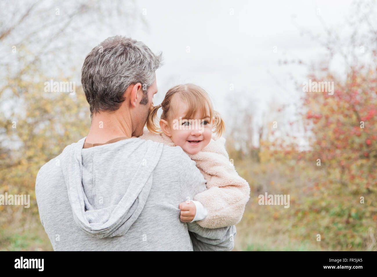 Father holding smiling toddler girl in park Stock Photo
