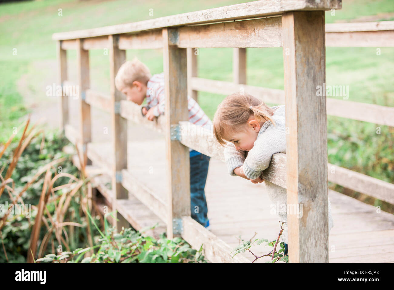 Toddler children leaning on footbridge railing in park Stock Photo
