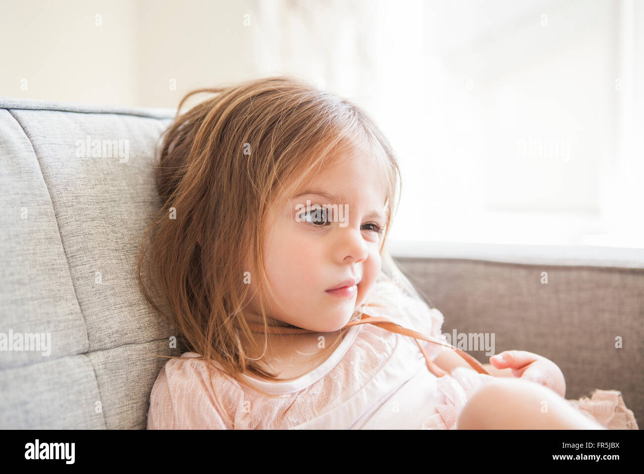 Toddler girl making a face on sofa Stock Photo