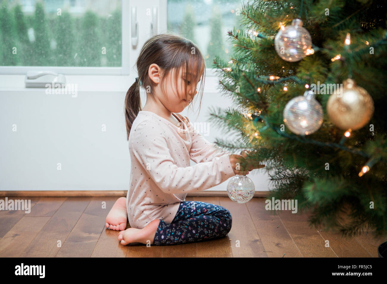 Toddler girl decorating Christmas tree Stock Photo