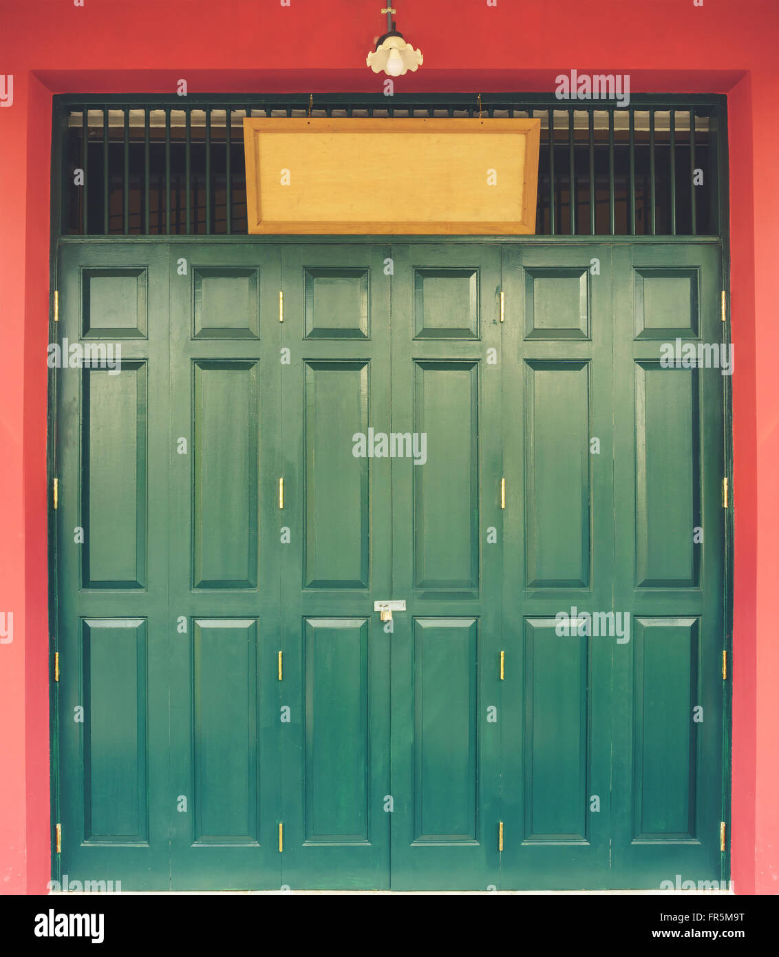 Vintage style green Chinese wooden door with blank wood shop label Stock Photo