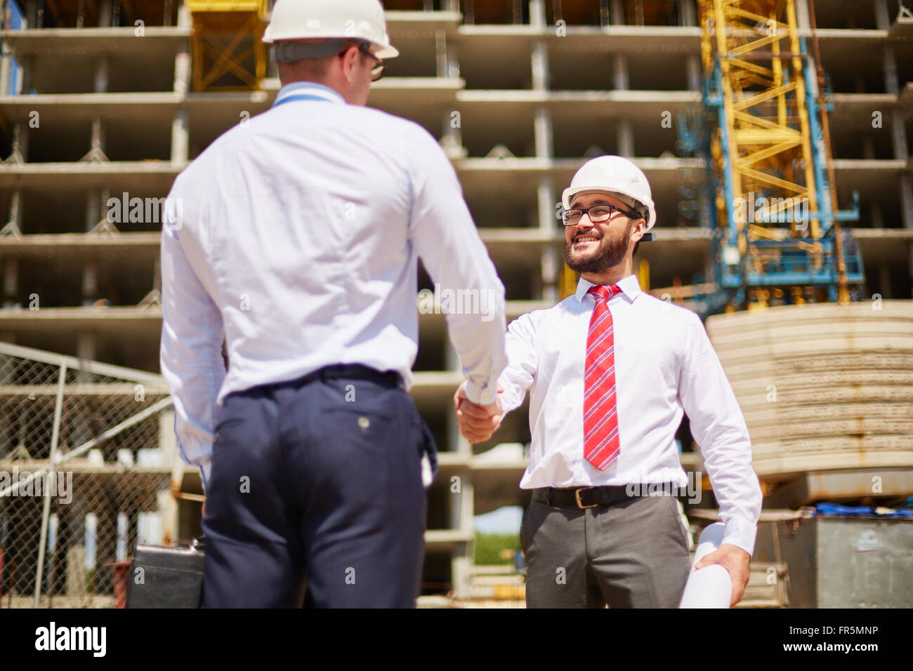 Young businessmen in hard hats shaking hands Stock Photo Alamy