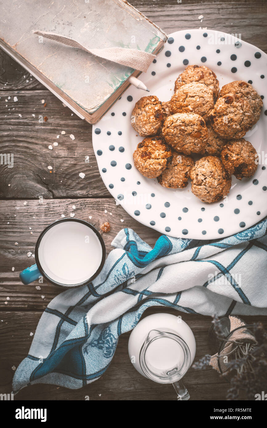 Book, oatmeal cookies and a cup of milk on old boards vertical Stock Photo