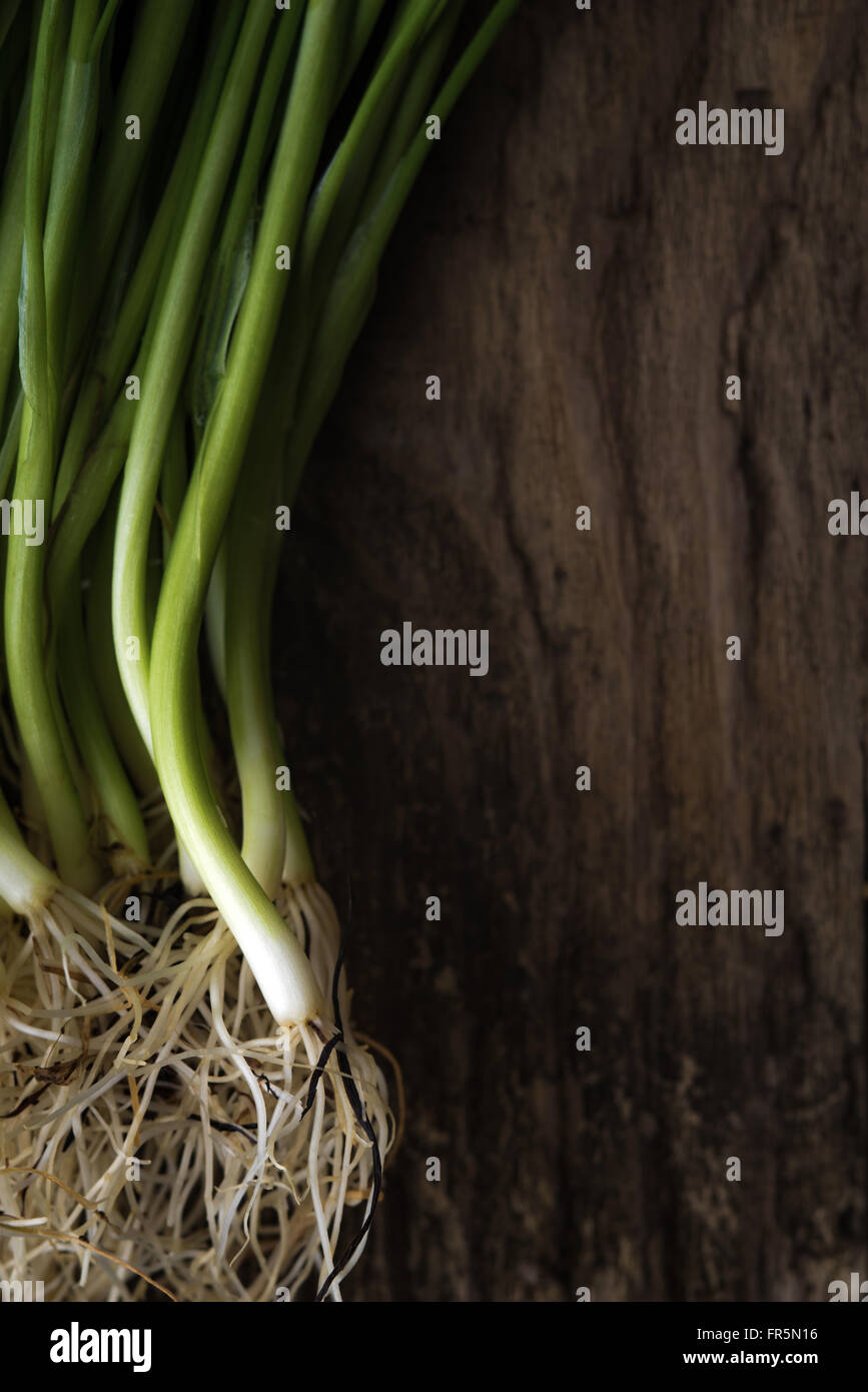 Green onion stalks and roots on a wooden table vertical Stock Photo Alamy