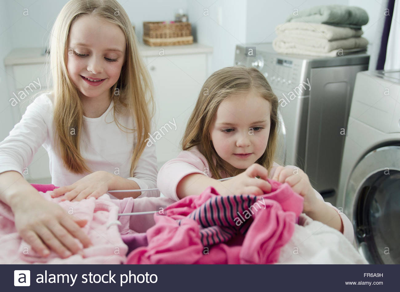 young sisters helping with laundry chores Stock Photo Alamy