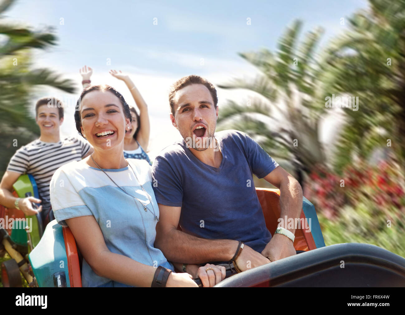 Young couple cheering on amusement park ride Stock Photo