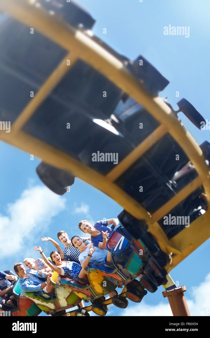 Friends riding roller coaster at sunny amusement park Stock Photo