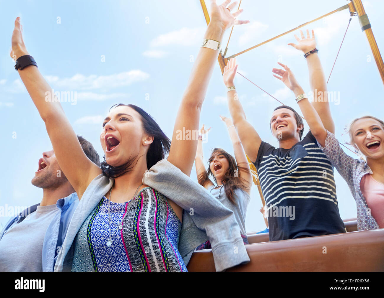 Friends cheering and riding amusement park ride Stock Photo