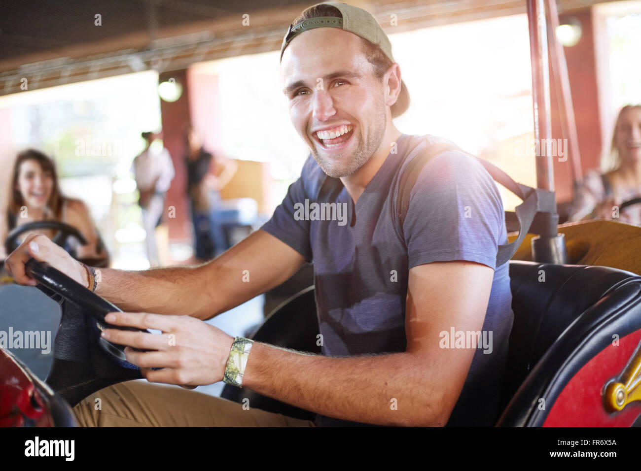 Laughing young man riding bumper cars at amusement park Stock Photo