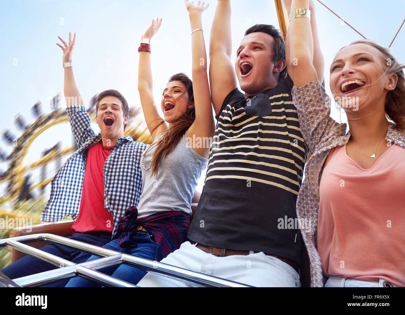 Cheering friends riding amusement park ride Stock Photo