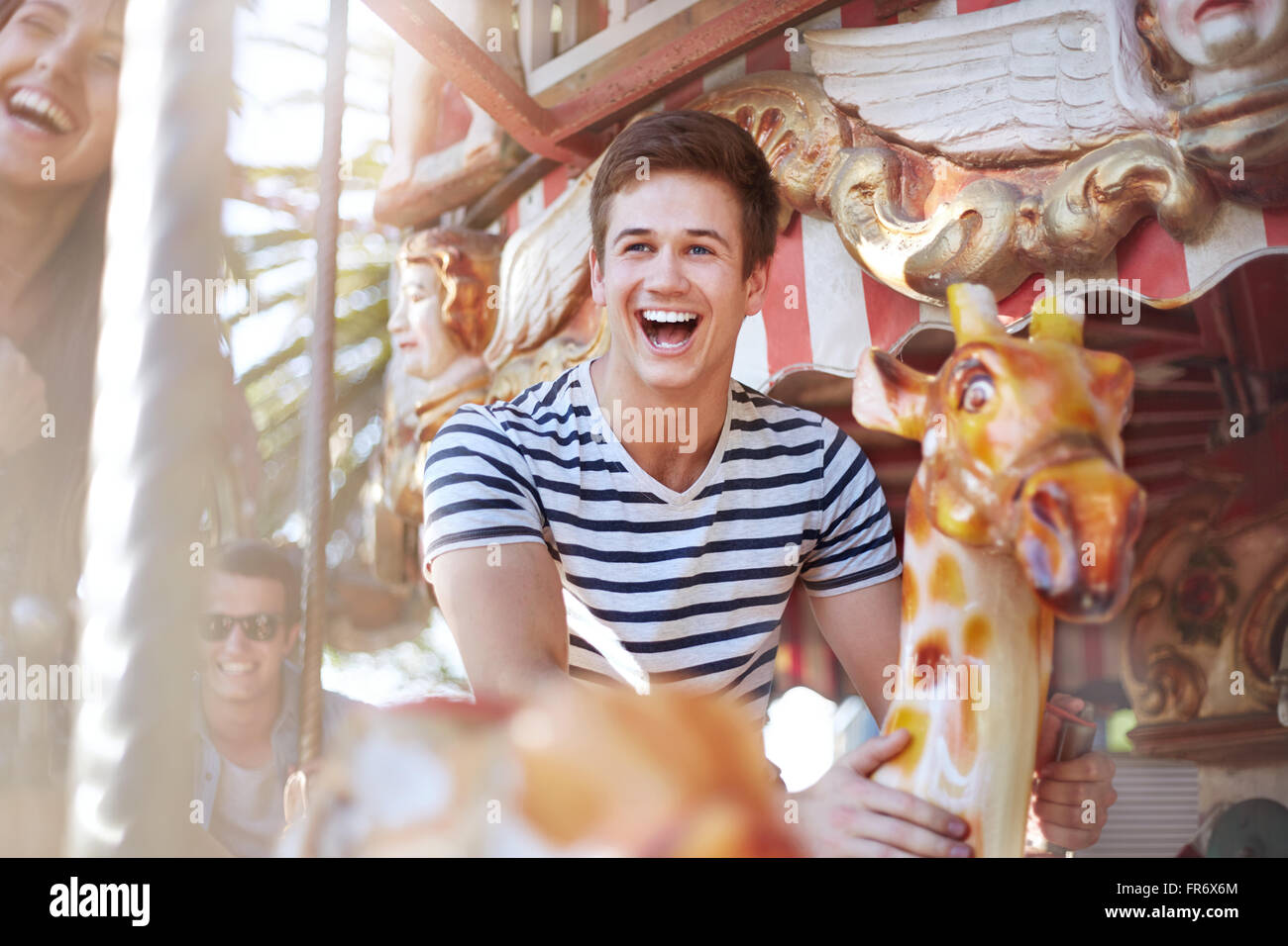 Enthusiastic young man riding carousel at amusement park Stock Photo