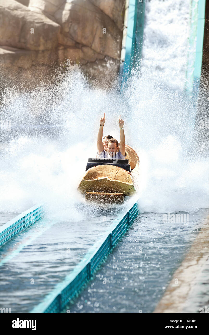 Enthusiastic young man riding water log amusement park ride Stock Photo