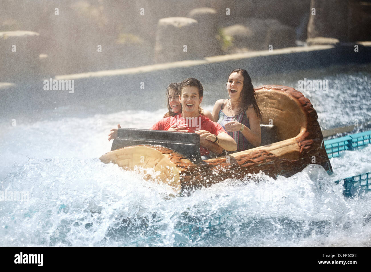 Wet friends laughing on water log amusement park ride Stock Photo