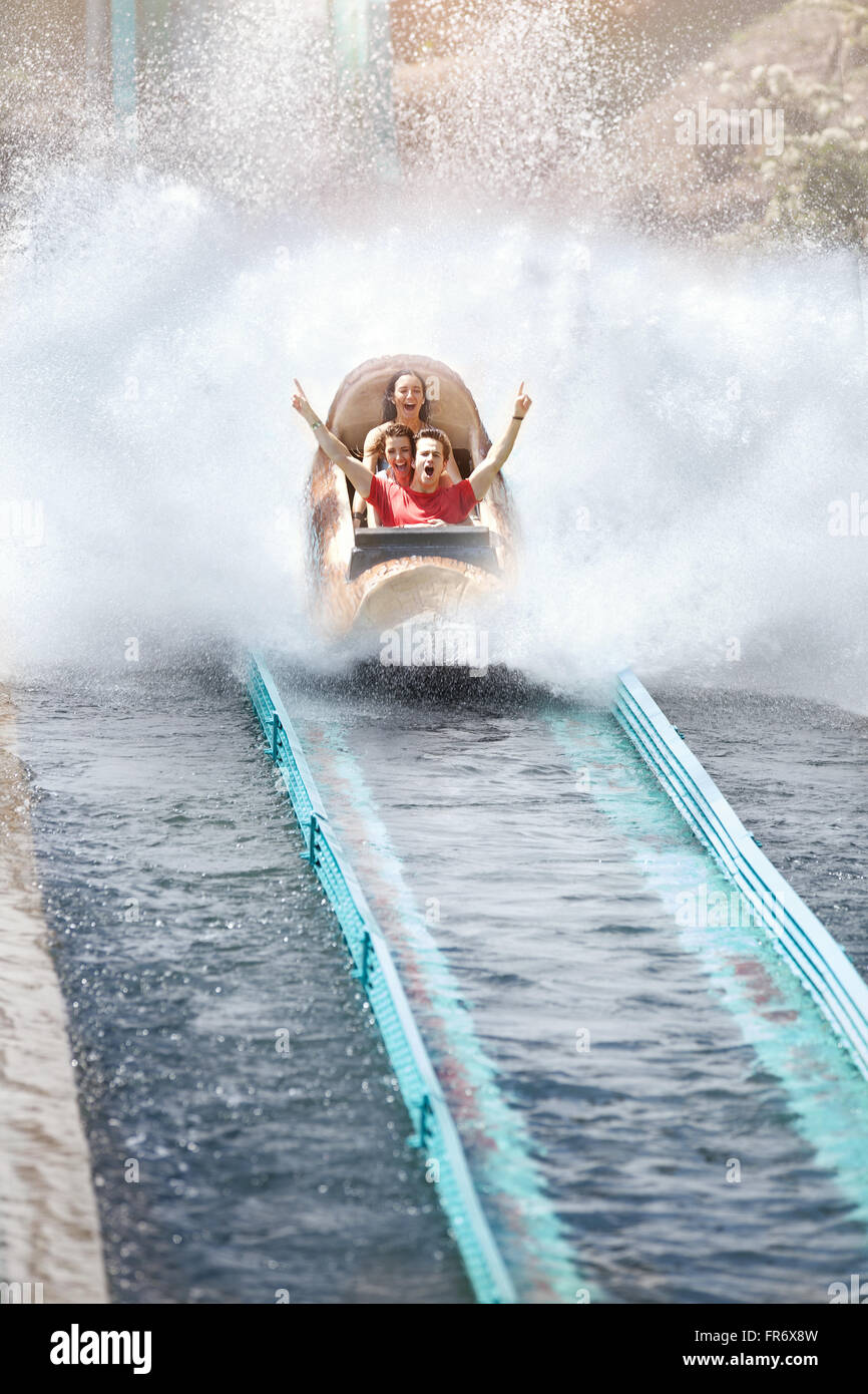 Enthusiastic friends cheering and riding water log amusement park ride Stock Photo