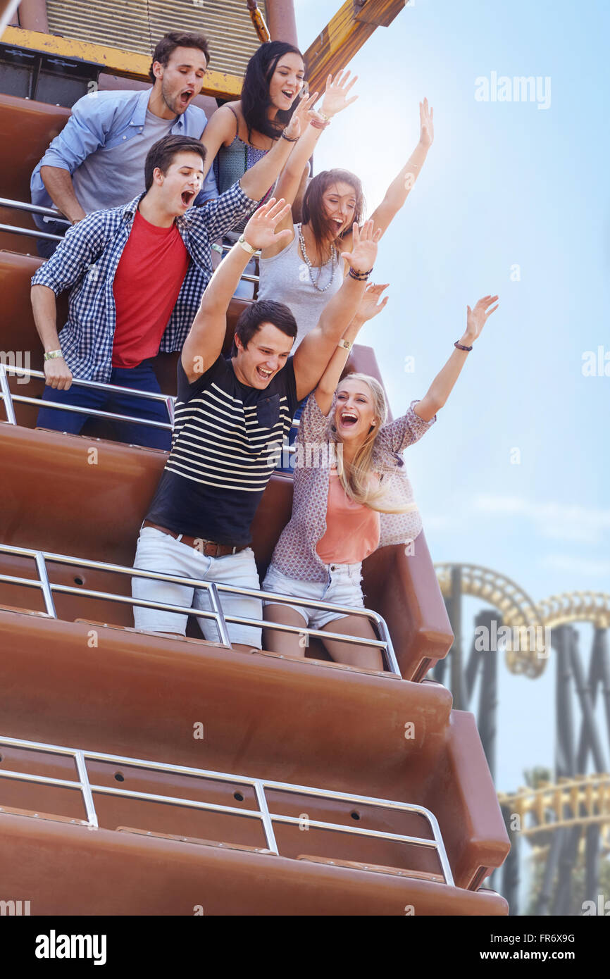 Enthusiastic friends cheering on amusement park ride Stock Photo