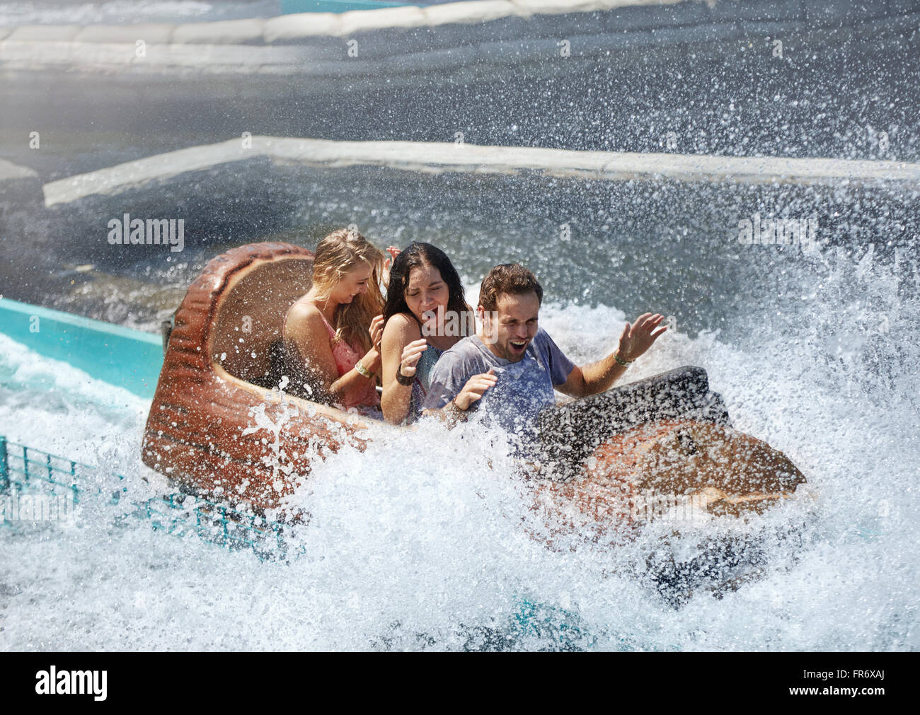 Friends getting splashed in water log amusement park ride Stock Photo