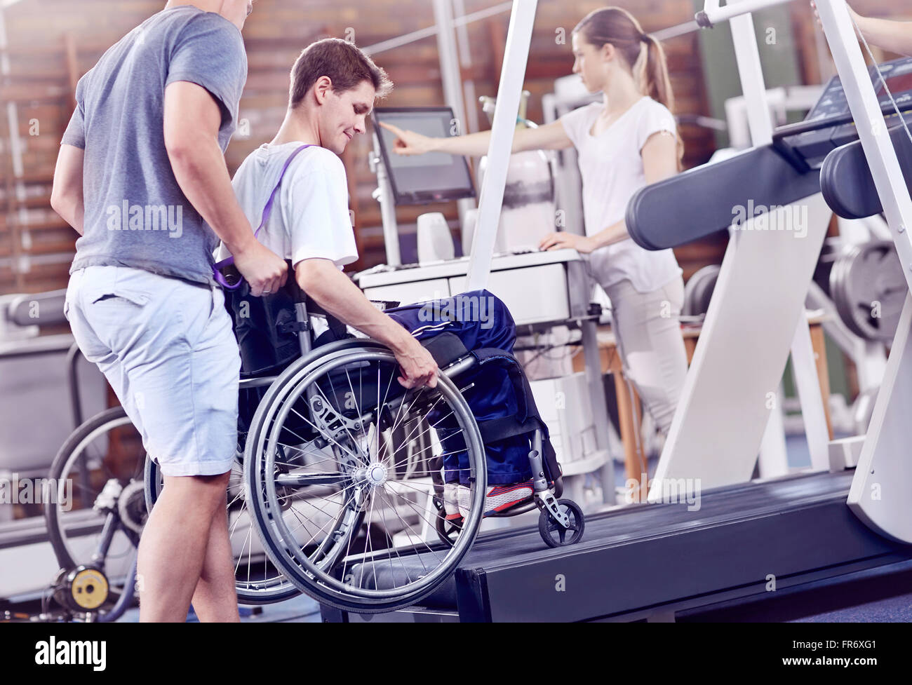 Physical therapists guiding man in wheelchair on treadmill Stock Photo